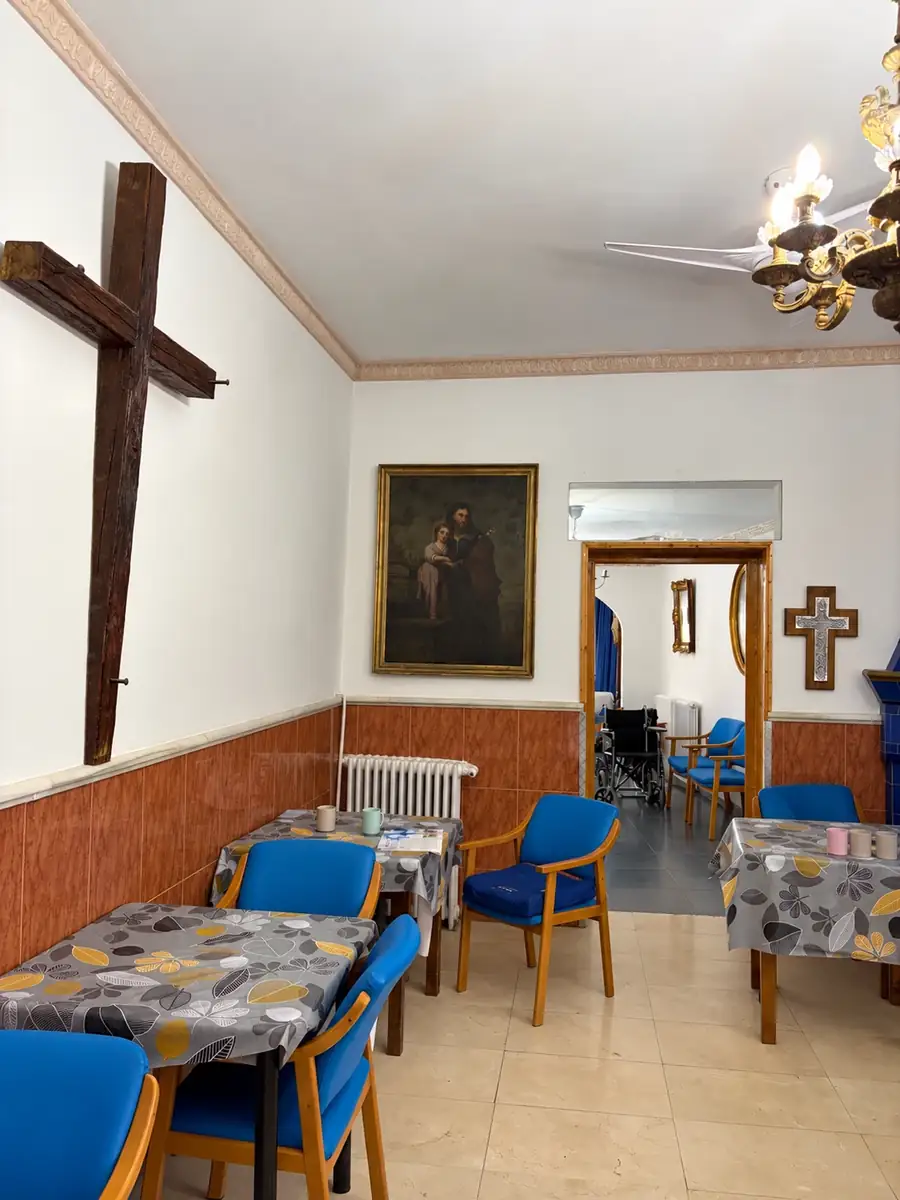 Salón con una cruz de madera y un cuadro religioso